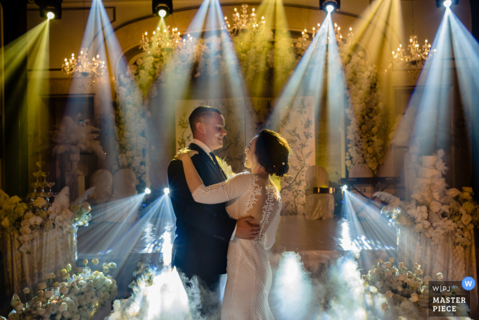 Bride and groom dance with an array of spotlights hitting the dancefloor