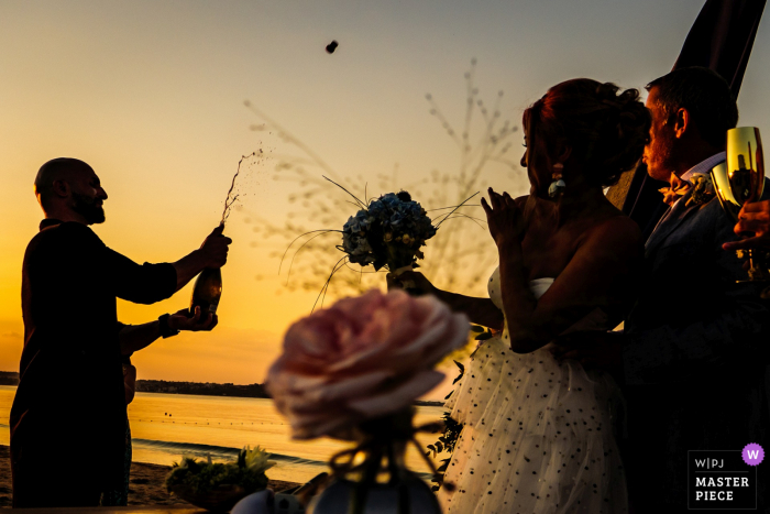 The best man is opening Champagne at sunset on the Papur Beach on the Black Sea