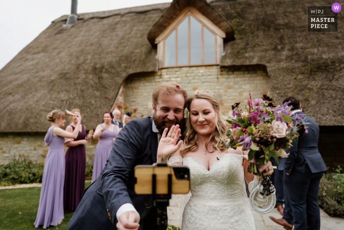 Blackwell Grange, Warwickshire wedding image of the bride and groom waving to their family and friends watching the wedding over Zoom Blackwell Grange, Warwickshire wedding image of the bride and groom waving to their family and friends watching the wedding over Zoom