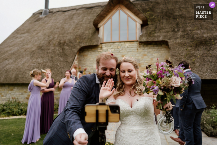 Blackwell Grange, Warwickshire wedding image of the bride and groom waving to their family and friends watching the wedding over Zoom