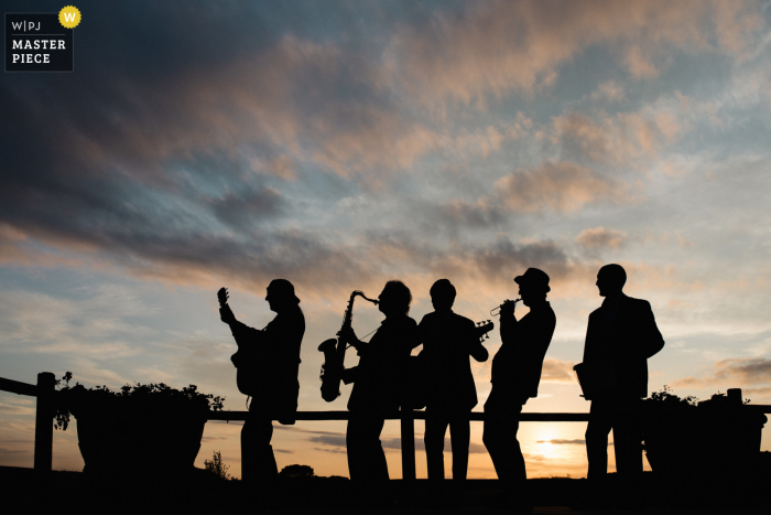 Immagine del matrimonio di sagoma della band che suona durante il tramonto presso la Tenuta Mocajo in Toscana, Italia