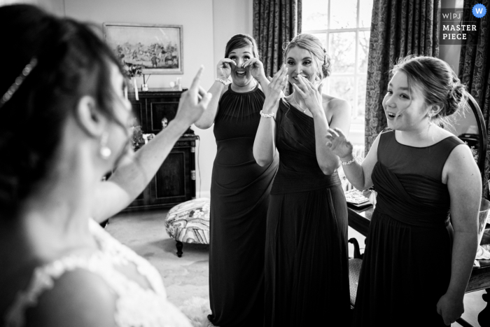 Bridal party reacts as they see the bride in her wedding dress at Iscoyd Park, UK