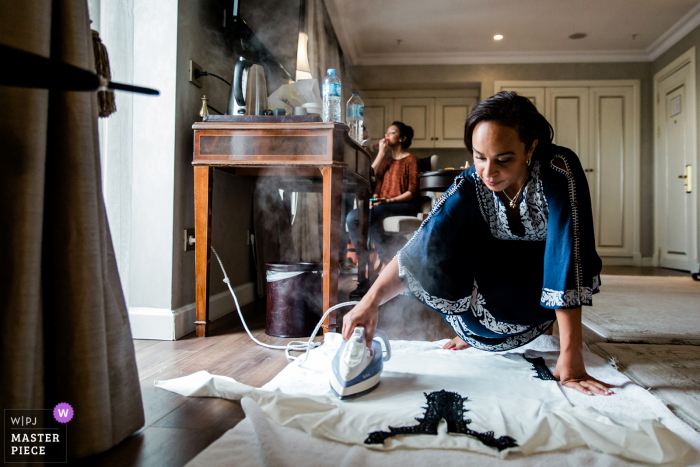 Bridemaid is ironing the groom's wedding costume as the bride gets ready at Rixos Pera Istanbul 