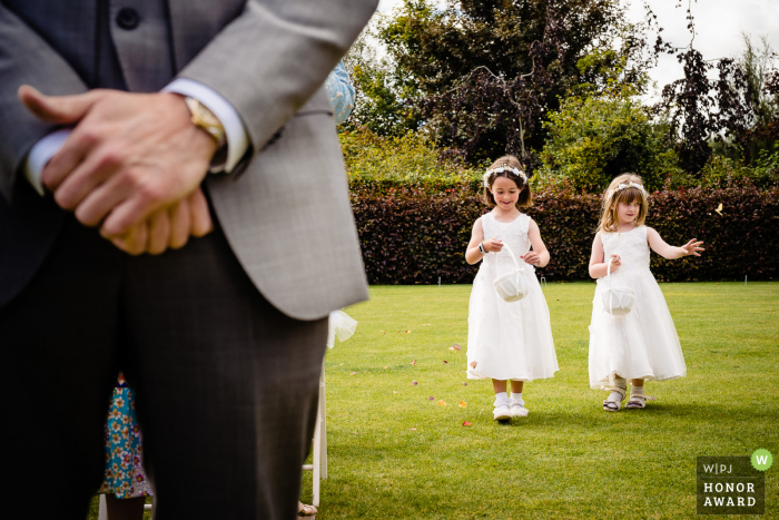 Cork, Irlanda, imagem da cerimônia de casamento ao ar livre das floristas caminhando pelo corredor enquanto deixam cair pétalas