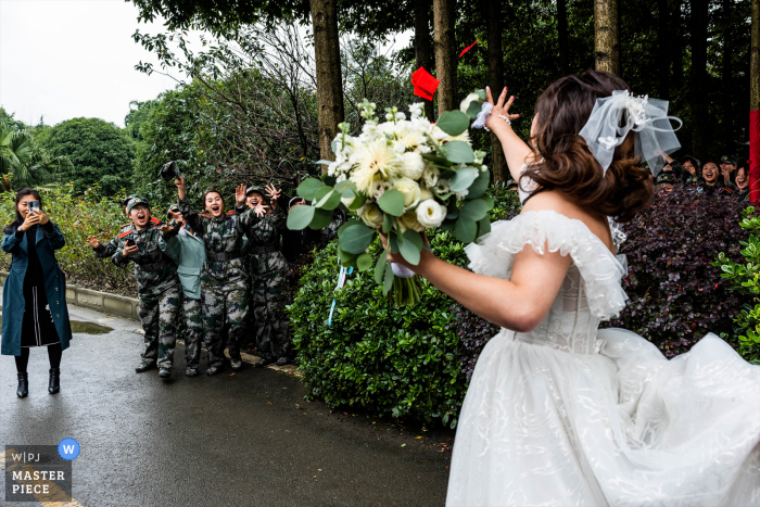 China bride is going to the ceremony site. On the way, she meets a group of military training students. They are wearing military uniforms. They are cheering for the bride. The bride throws a red envelope with RMB to them to express her gratitude. China bride is going to the ceremony site. On the way, she meets a group of military training students. They are wearing military uniforms. They are cheering for the bride. The bride throws a red envelope with RMB to them to express her gratitude.
