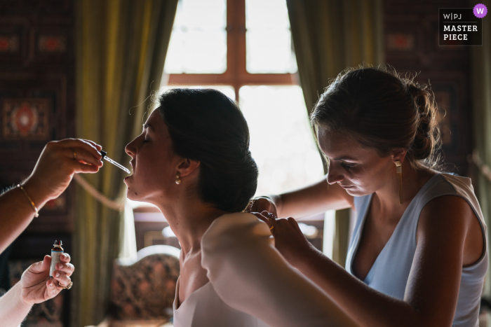 La novia recibe ayuda con su vestido y lápiz labial antes de su boda en Brissac-Quincé, Francia