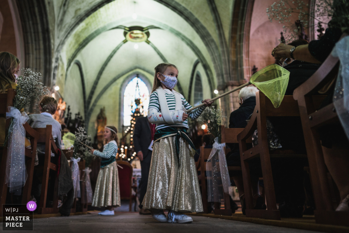 Huwelijksfotografie vanuit een kerk Saint-Suliac, Frankrijk Ceremonie van bloemenmeisjes die de gasten verzorgen