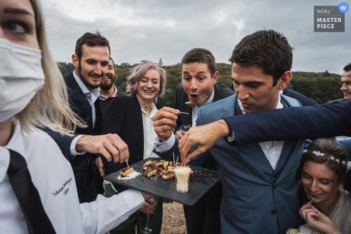 Huwelijksfoto van een Miniac Morvan, Frankrijk Cocktailuur van gasten die eten uit een dienblad van een verkoper eten