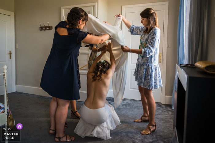 Die Braut bekommt Hilfe beim Anziehen ihres Hochzeitskleides für ihre Zeremonie in Frankreich