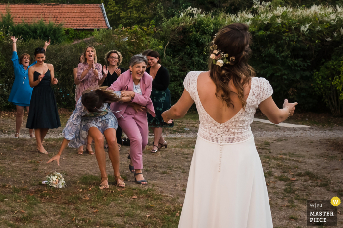 Fotografia di matrimonio da un luogo di ricevimento Auvergne-Rhône-Alpes di donne ospiti che litigano per il bouquet della sposa quando vengono lanciate