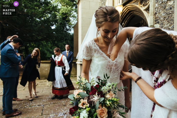 bruidsmeisje haalt confetti uit de jurk van de bruid in de Streatham Church