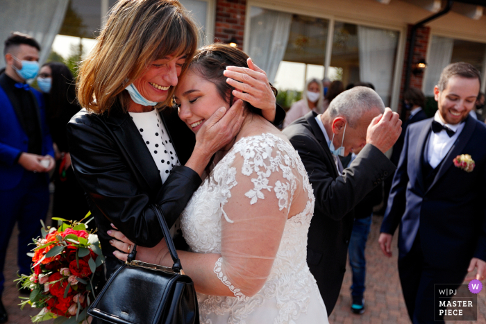 Inmediatamente después del lanzamiento del arroz, la novia y su madre se abrazan emocionadas en la Antica Cascina Margherita en Barbania, Torino, Italia.