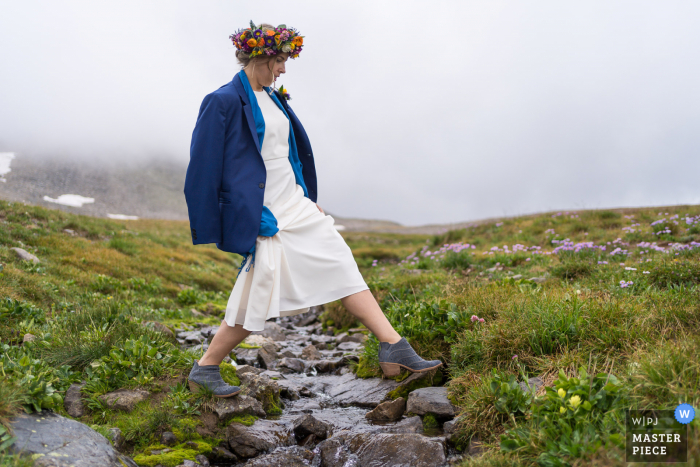 Huwelijksfotografie van een openluchtceremonie in Colorado Locatie van de bruid die de stroom oversteekt naar de ceremonieplaats