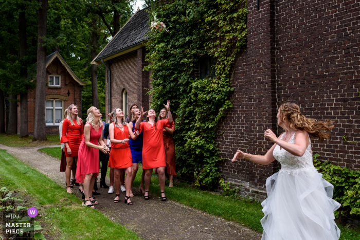 Fotografia di matrimonio da un luogo di ricevimento olandese della sposa che lancia il suo bouquet