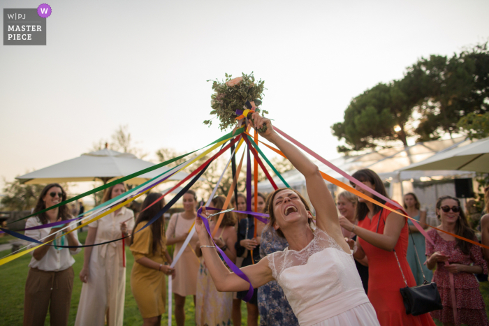 Fotografia di matrimonio dal ricevimento all'aperto presso il luogo del ricevimento: Villa La Tosca, Francia della Sposa che le consegna il bouquet