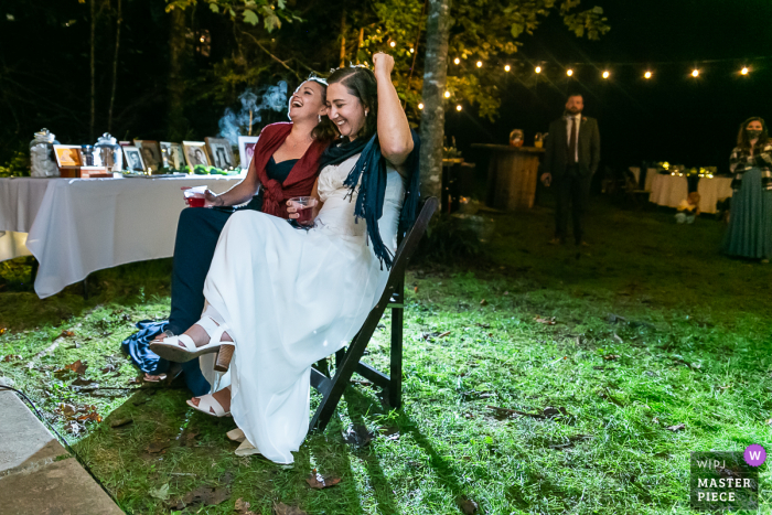 Huwelijksfotografie van Wit's End, Ellijay, GA van de bruiden die van een afstand op een toast reageren