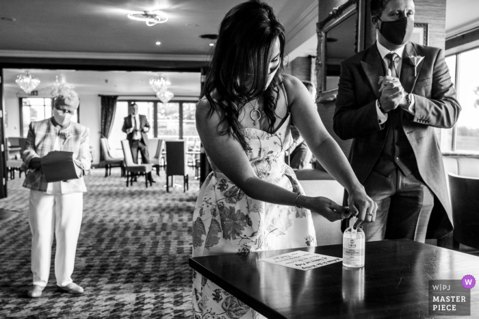 Fotografia de casamento de convidados em East Riding of Yorkshire aplicando desinfetante para as mãos