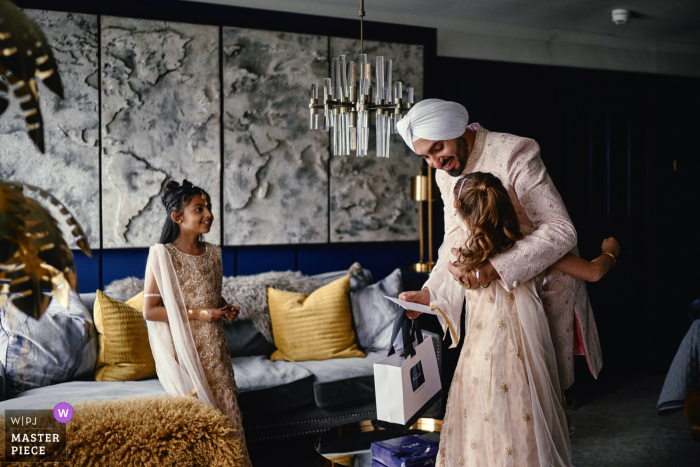 The bride's daughter brings the groom a wedding message and gift whilst getting ready before his wedding at The Elms Hotel, Kidderminster, UK