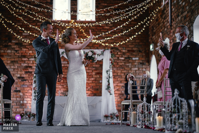 Hotel Chester Doubletree by Hilton, Chester, Wielka Brytania. Zdjęcie z ceremonii ślubnej, na którym panna młoda i pan młody machają do transmisji na żywo, gdy wychodzą z ceremonii ślubnej