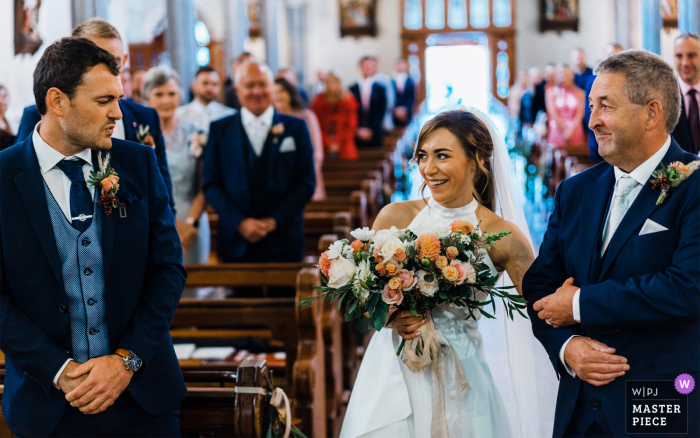 El novio da una gran reacción a la novia en la parte superior del pasillo de una iglesia en el condado de Meath, Irlanda