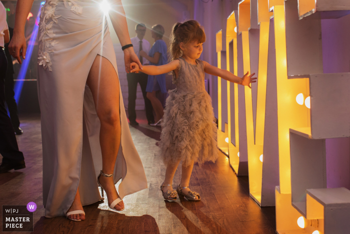 Krakow Malopolskie wedding photography of a young girl at the reception with a giant sign reading 'love'