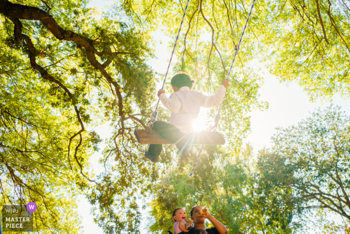 Sacramento foto del matrimonio nel cortile di un bambino piccolo che guarda suo fratello oscillare