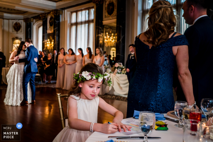 The flower girl colors while the bride and groom do their first dance at The Belvedere in Baltimore, Maryland