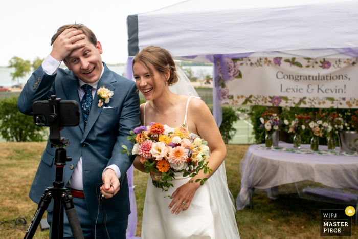 Coronavirus, COVID, imagen de boda en el patio trasero de Madison del novio y la novia hablando a través del zoom con sus padres después de casarse