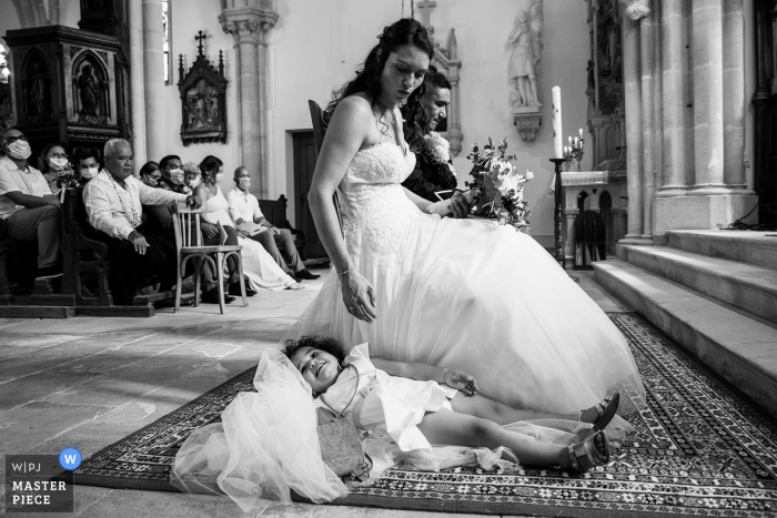 Immagine del matrimonio della Chiesa di Gondrecourt della figlia della sposa che posa sul suo vestito durante la cerimonia