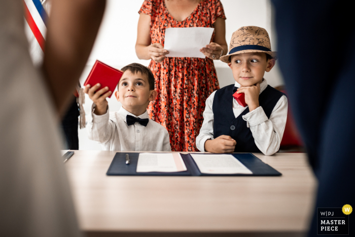 Due figli aspettano pazientemente e pronti a consegnare le fedi ai loro genitori durante una cerimonia in municipio