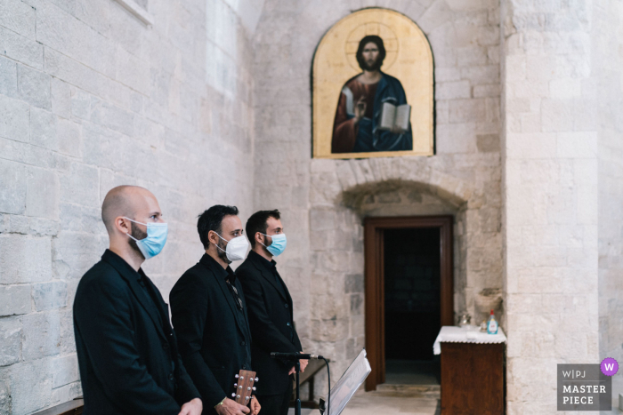 Afbeelding van het kerkhuwelijk in Puglia van drie mannen in covid-maskers die aan de zijkant staan