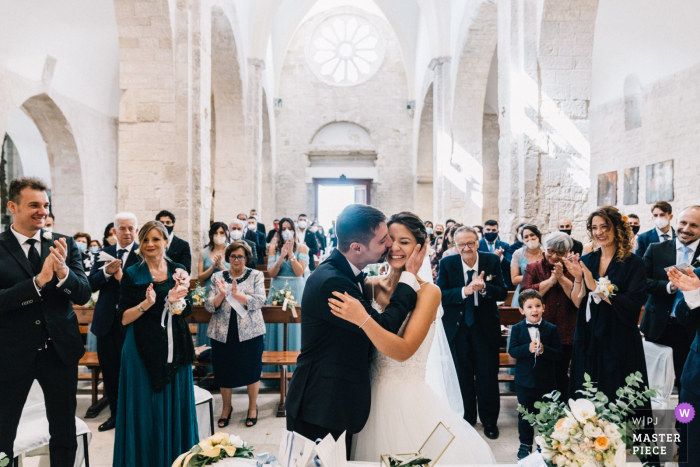 Immagine di cerimonia in chiesa pugliese dello sposo che bacia la sua sposa