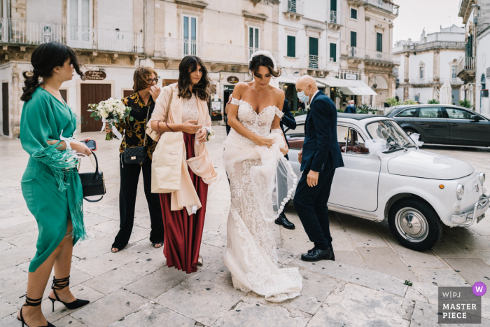 Puglia bride and lady attendants arriving while being hit by high winds