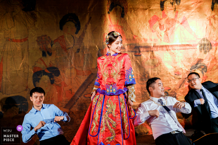 Imagem de casamento de uma noiva dançando com uma túnica de fênix durante sua recepção em um salão de banquetes em Taiwan