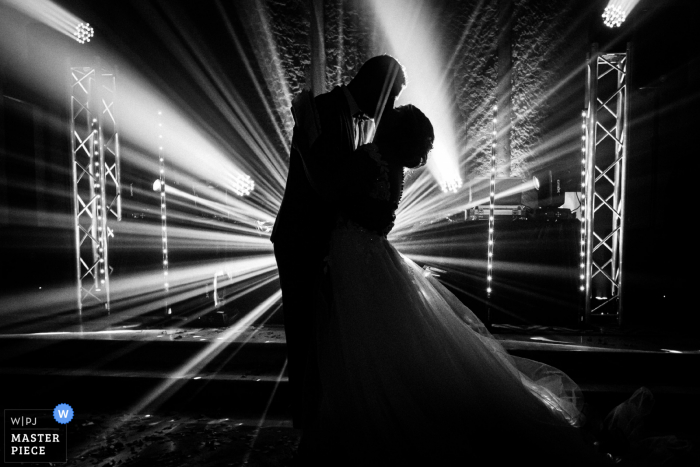 French black and white wedding photo of the bride and groom dancing with the DJ lights beaming around them