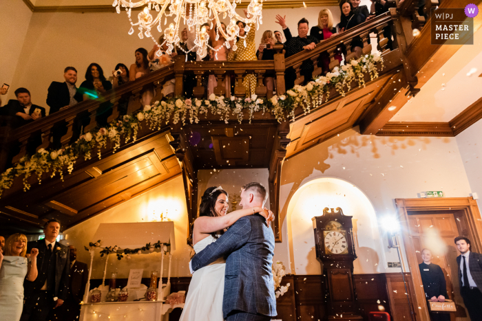 La novia y el novio son bañados en pétalos de flores por sus invitados en el Holmewood Hall en Peterborough.