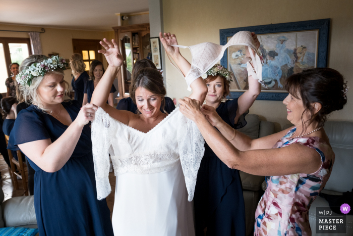 Turenne foto de la boda de la novia poniéndose el vestido con familiares y amigos para ayudar