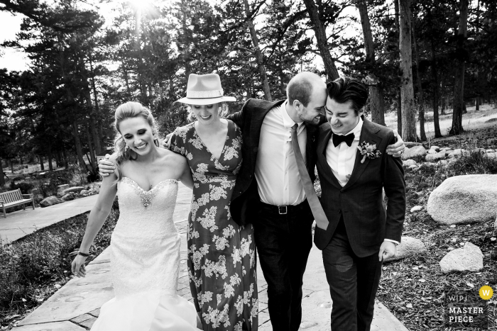 Fotografia di matrimonio in Colorado da Della Terra Mountain Chateau, Estes Park della sposa e dello sposo che camminano lungo il sentiero con gli invitati al matrimonio