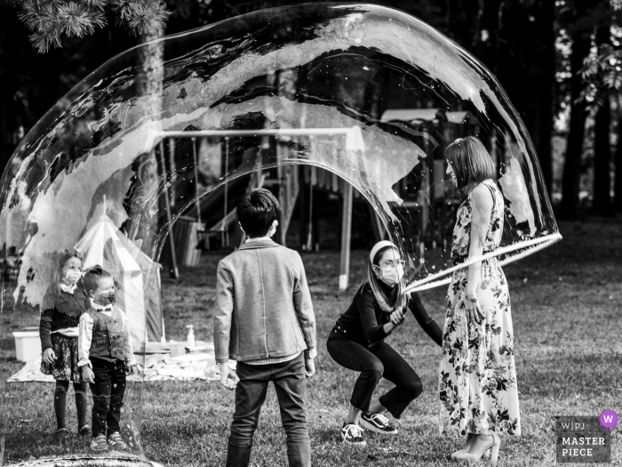 Fotografía de boda del Chalet del Parco en Italia - Milano mostrando a un invitado jugando con jabón de burbujas