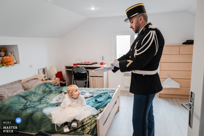 Fotografia de casamento dos preparativos militares em casa em Chambéry enquanto o noivo terminava de se arrumar na frente de sua filha