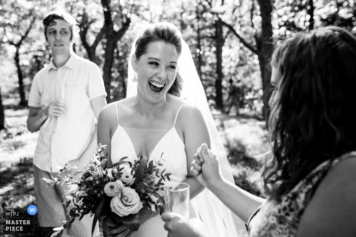 Una foto de boda de Quebec desde Montreal de una novia emocionada siendo felicitada por un amigo después de la ceremonia de boda en el parque