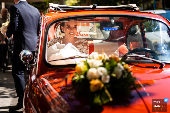 Foto de boda de Trieste de Italia que muestra a la novia feliz en el coche rojo