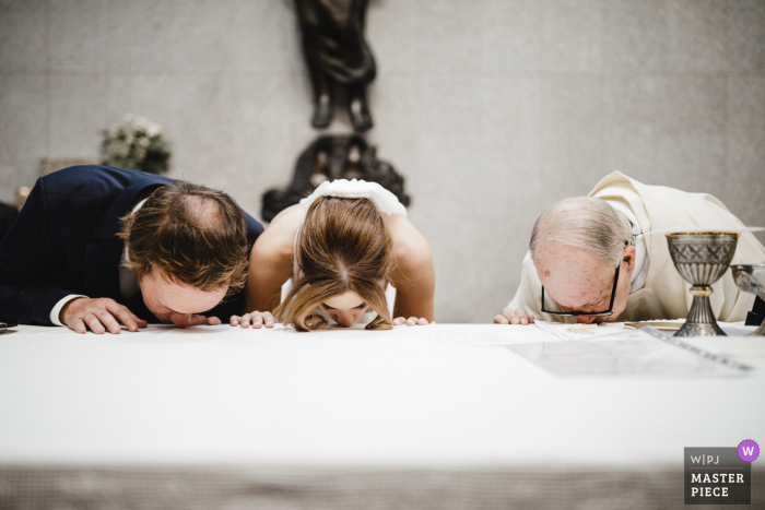 Porto - Portogallo fotografia di matrimonio della coppia e del prete che si baciano al tavolo della chiesa