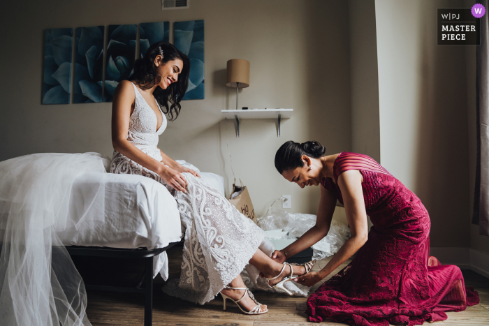 Fotografia di matrimonio in Virginia da Arlington che mostra la mamma che aiuta la sposa a prepararsi con le sue scarpe