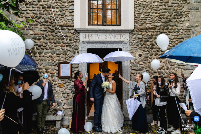 Um fotógrafo de casamento Verbano-Cusio-Ossola capturou esta saída do casal na Igreja do Piemonte sob guarda-chuvas e balões