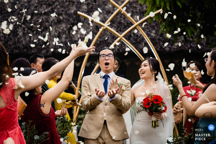 Vietnam wedding Ceremony photography of the bride and groom exiting under flying flower petals