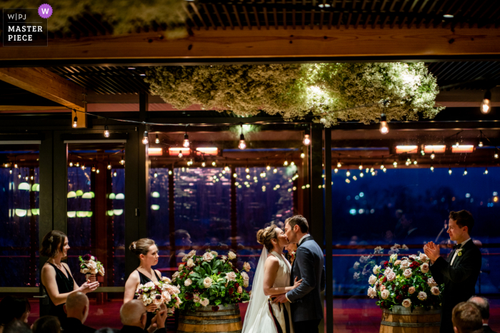 A Virginia wedding photographer captured this District Winery bride and groom first kiss under baby's breath floral clouds A Virginia wedding photographer captured this District Winery bride and groom first kiss under baby's breath floral clouds