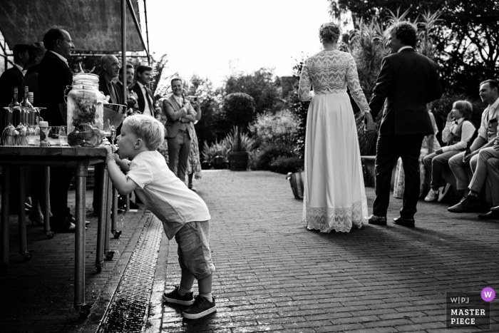 Reportage fotografico di matrimonio da un luogo di ricevimento ad Amsterdam di un bambino che beve acqua durante il discorso