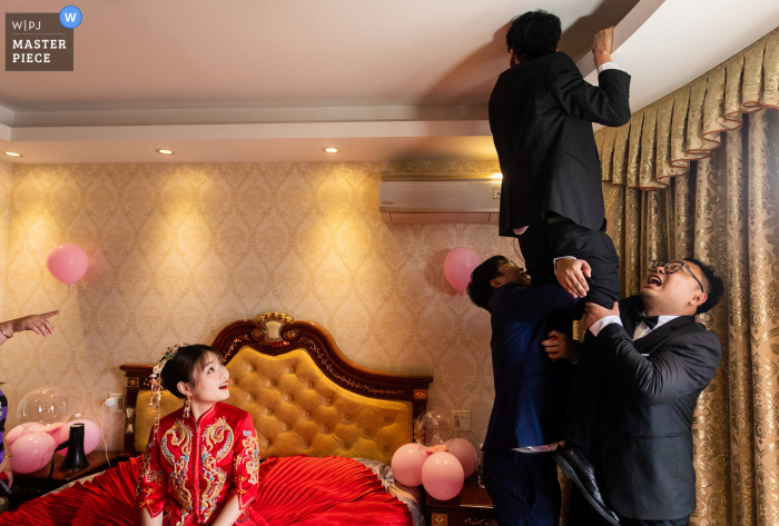 Le photographe de mariage Jinhua a capturé cette image amusante au domicile de la mariée du Zhejiang des meilleurs hommes à la recherche des chaussures de mariage de la mariée