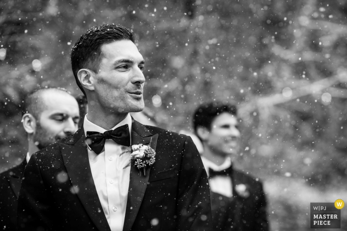 El fotógrafo de bodas de California capturó esta imagen nevada al aire libre en Granlibakken Resort: Tahoe City, CA de El novio reaccionando al ver a su novia por primera vez en su ceremonia.